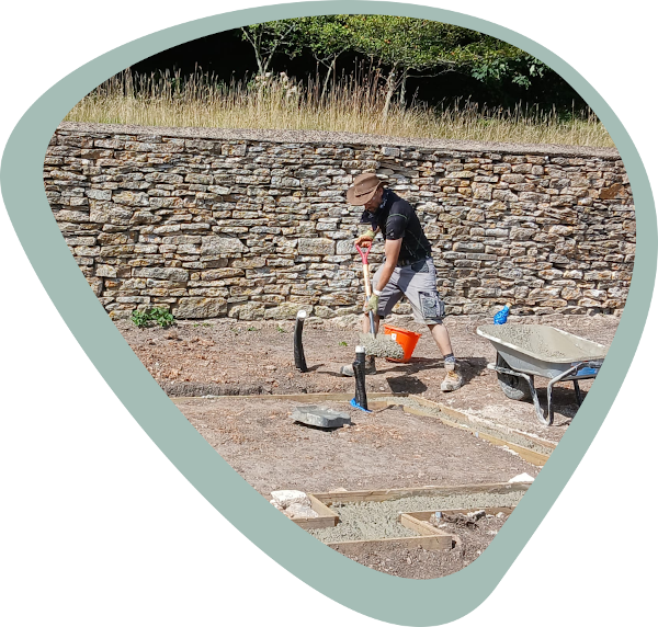 A handyman preparing form boards prior to laying concrete for a greenhouse foundation.