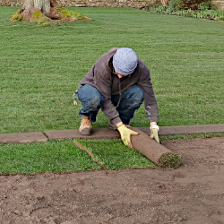 A handyman laying grass turf on a private estate in the Cotswolds