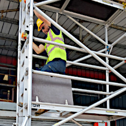 A handyman climbing down from a scaffold tower