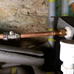 A copper pipe with an isolator valve connected to a water tank in an attic 